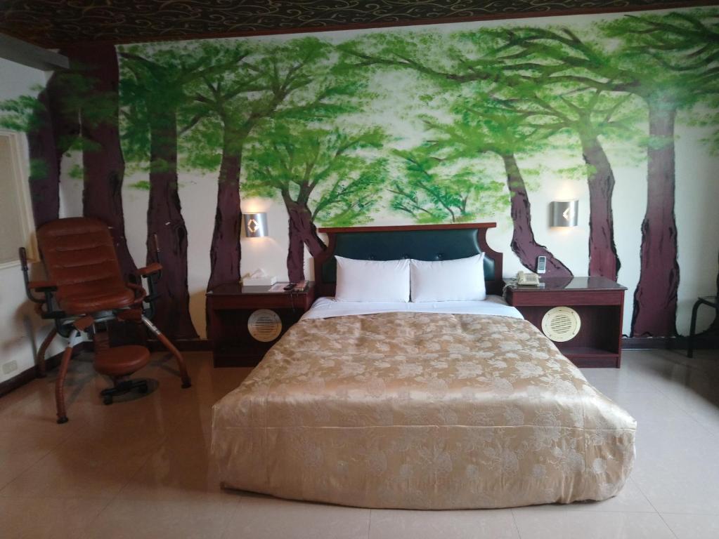 sypialnia z łóżkiem z obrazem drzew na ścianie w obiekcie Hua Du Motel w mieście Jiji