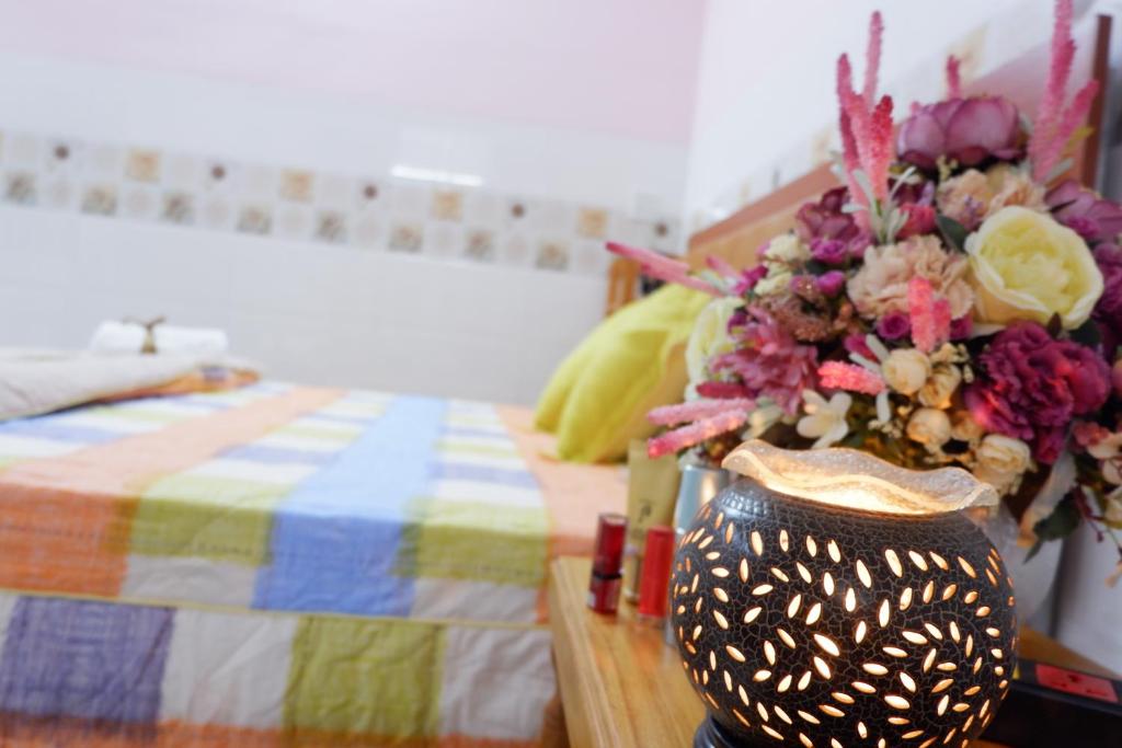 un jarrón de flores en una mesa junto a una cama en Thịnh's House en Can Tho