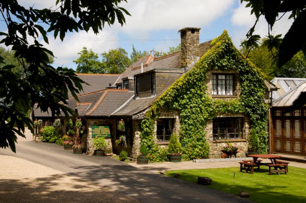 ein mit Efeu bedecktes Haus mit einem Picknicktisch davor in der Unterkunft Lakeview Manor in Dunkeswell