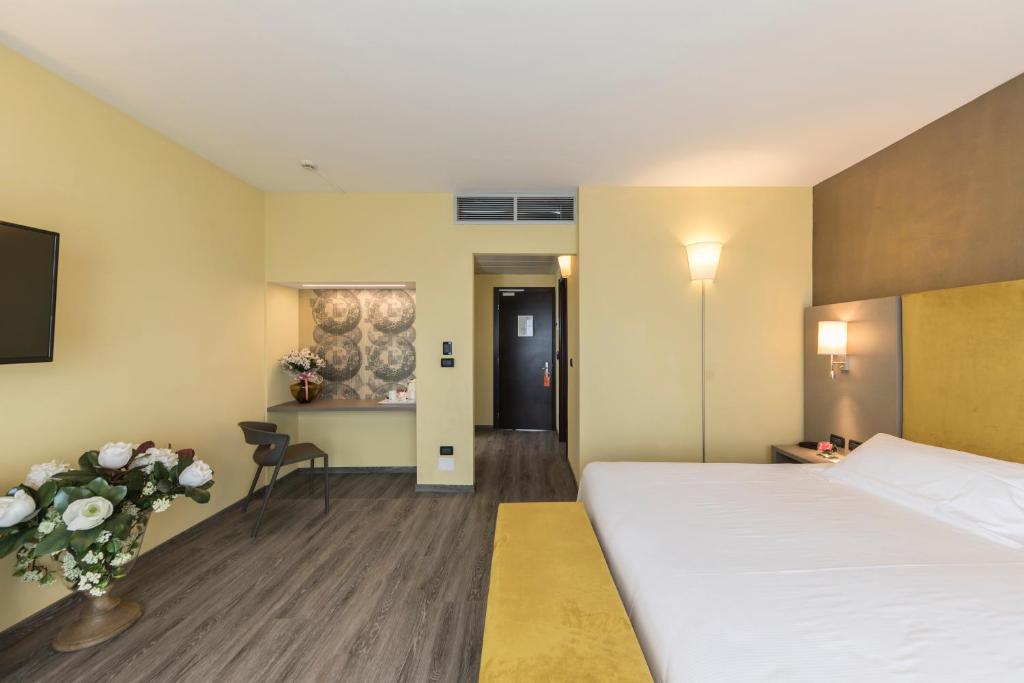 イモラにあるHotel Donatello Imolaの大きなベッドとテーブルが備わるホテルルームです。