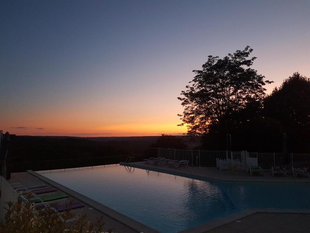 una piscina con puesta de sol en el fondo en Domaine des Compouzines, en Montignac