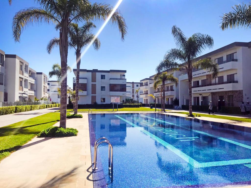 una piscina con palmeras y edificios en Marbella Beach location pour famille 2 chambres en Minaret de Mansuria