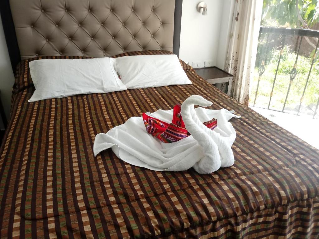 Una cama con toallas y cisnes. en Hotel Quilla House 2, en Urubamba