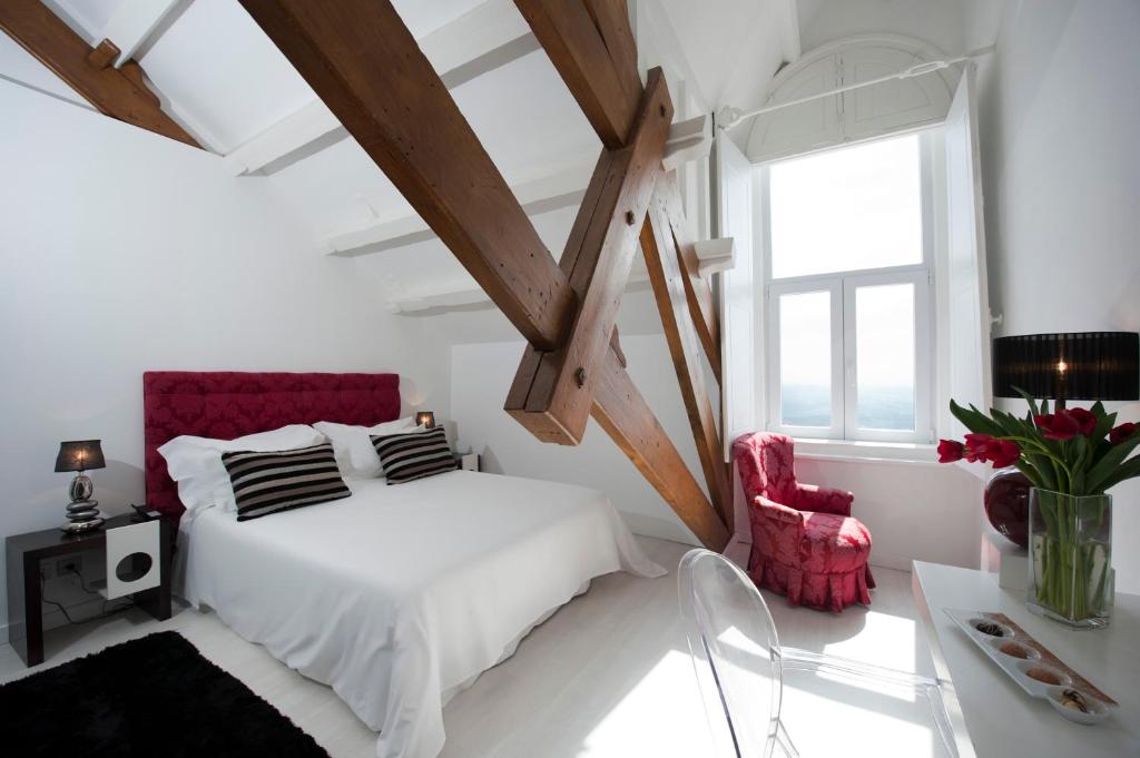 a bedroom with a white bed and a red chair at Farol Hotel in Cascais
