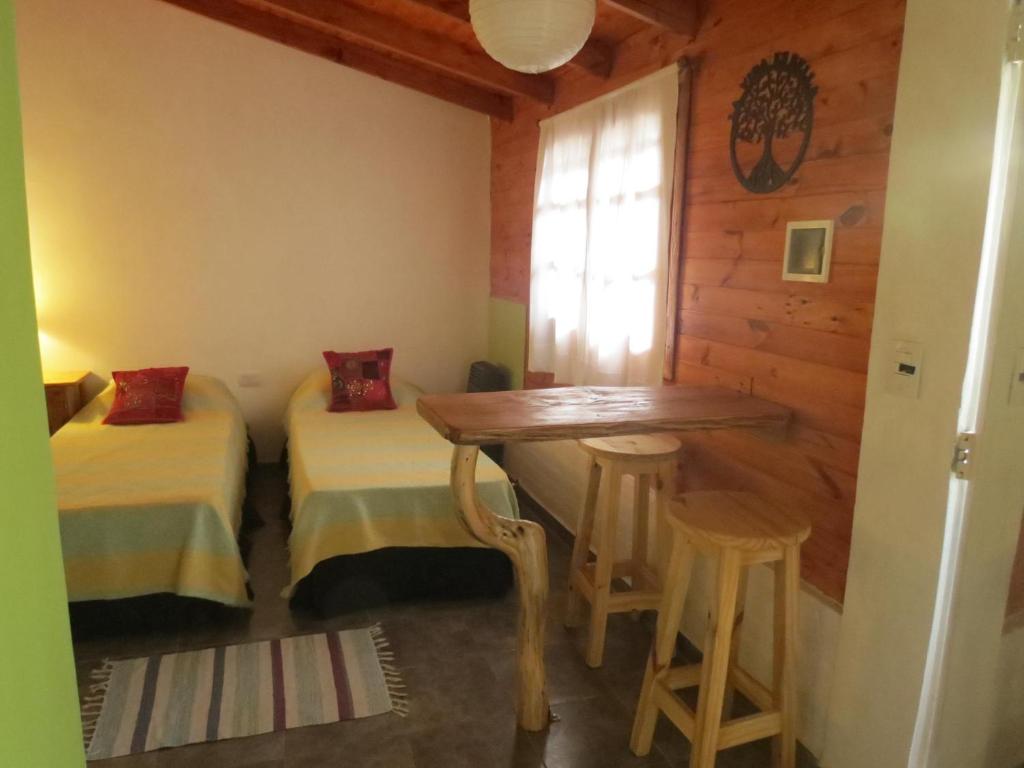 um quarto com duas camas e uma mesa e banco em La Casa De La Abuela Departamentos em El Bolsón