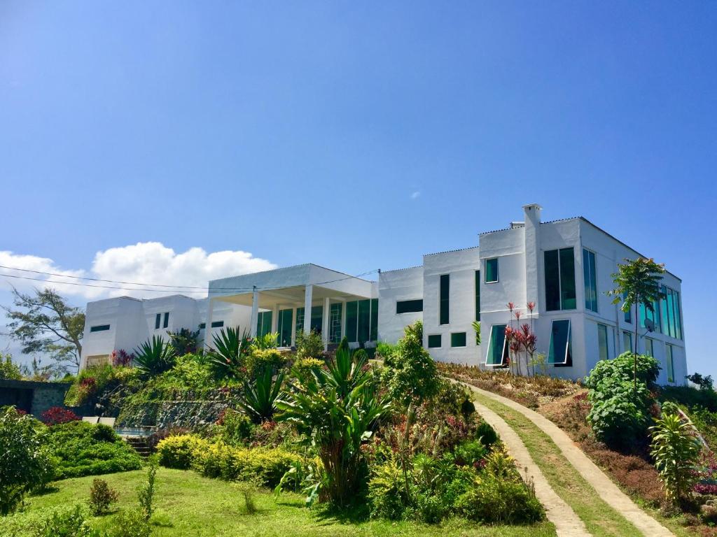 ヌワラエリヤにあるSingha Sanasa Luxury Homestayの緑の窓と庭のある白い家