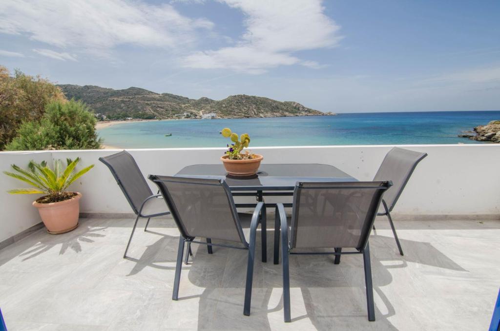 
a table with chairs and a patio with a view of the ocean at Hotel Delfini in Mylopotas
