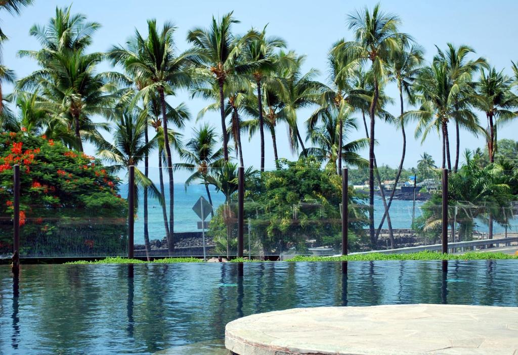 una piscina de agua con palmeras en el fondo en Beach Villas at Kahalu'u en Kailua-Kona