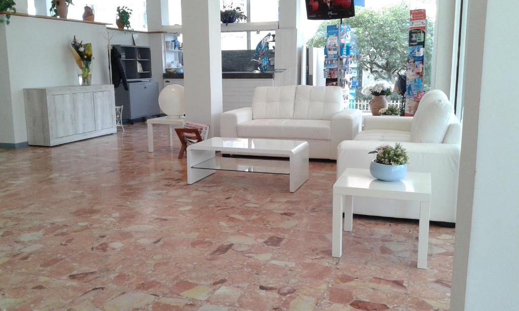 una sala de estar con muebles blancos y suelo de mármol. en Hotel Ambasciata, en Riccione