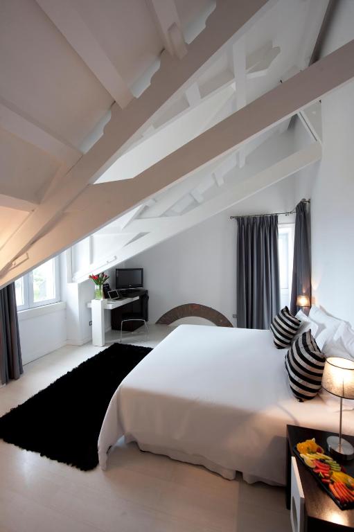 a white bedroom with a large bed and a desk at Farol Hotel in Cascais