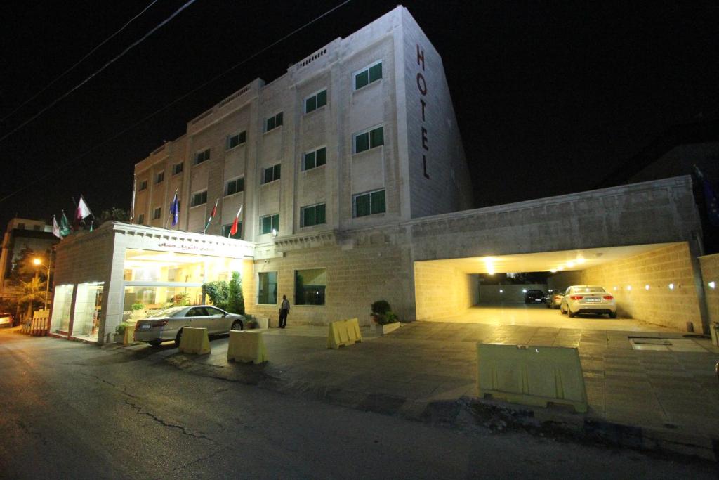 a building with cars parked in a parking lot at night at Al Thuraya Hotel in Amman