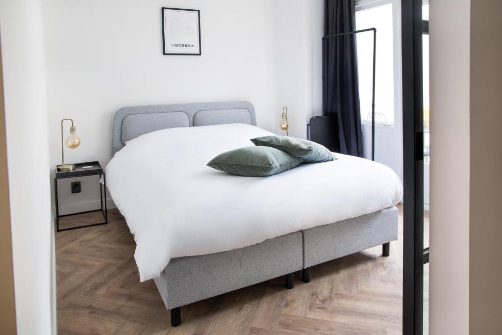 a bedroom with a white bed with two pillows on it at Maison Bon Apartments in Den Bosch