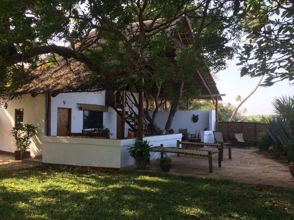 une maison avec un toit de chaume et une terrasse dans l'établissement Villa Matalai, à Tanga