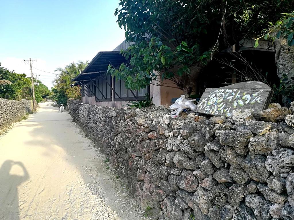 a stone wall next to a sidewalk next to a street at Taketomijima Guesthouse and je Taime in Taketomi