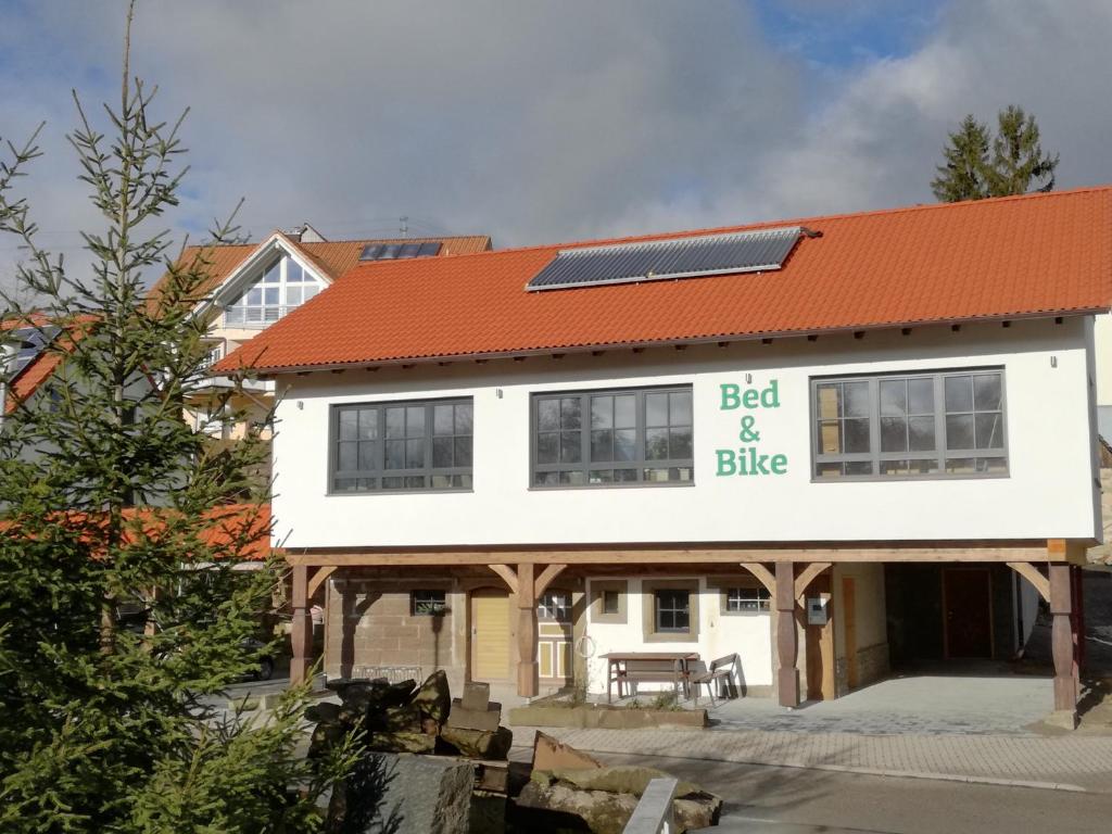 un bâtiment blanc avec un toit rouge et un panneau dans l'établissement Bed & Bike, à Trichtingen