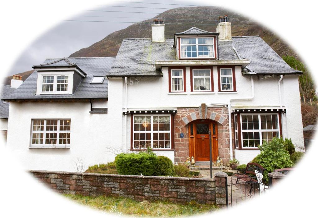 ein weißes Haus mit einer roten Tür in der Unterkunft Edencoille Guest House in Kinlochleven