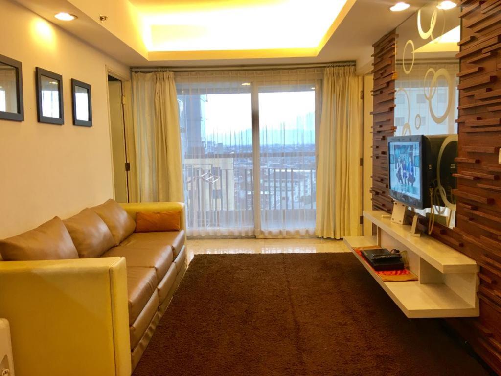 - un salon avec un canapé et une télévision dans l'établissement Apartemen Braga City Walk, à Bandung