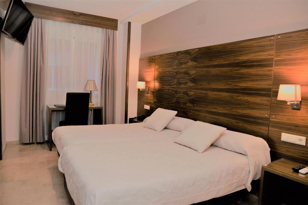 シウダー・レアルにあるHotel Escuderoの大きなベッドと木製の壁が備わるホテルルームです。