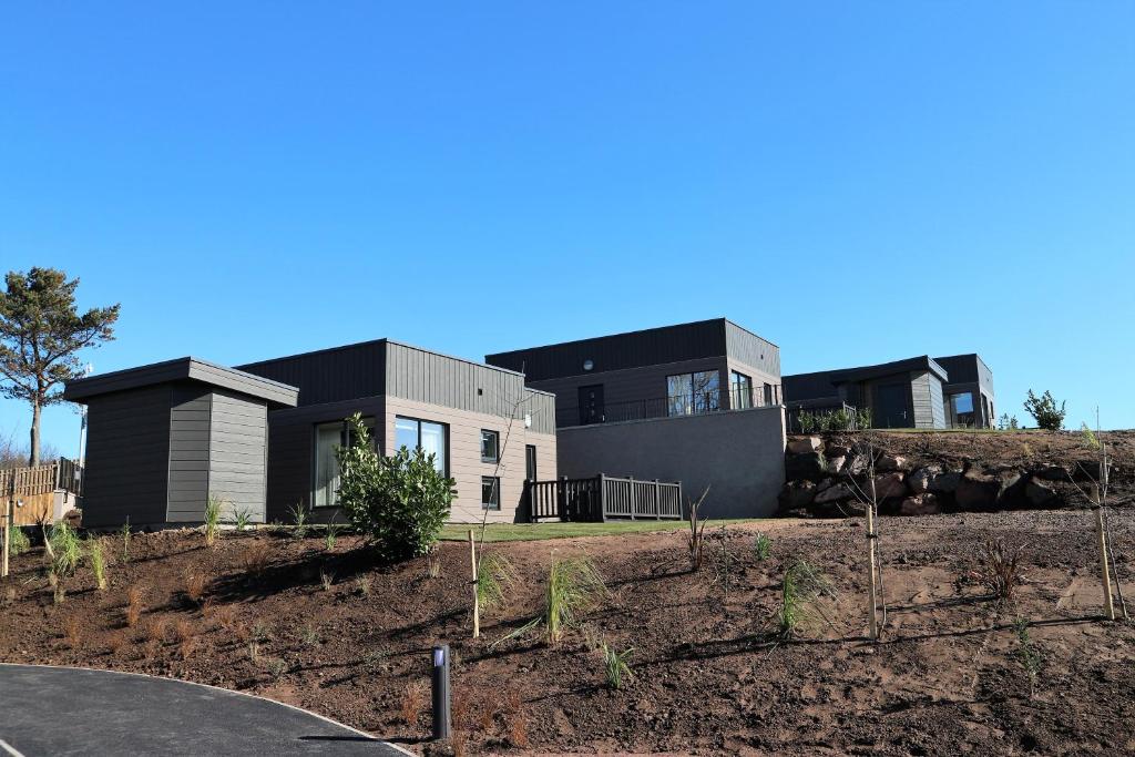 a house on top of a hill with a yard at Dalriada Lodges Skatie in Stonehaven