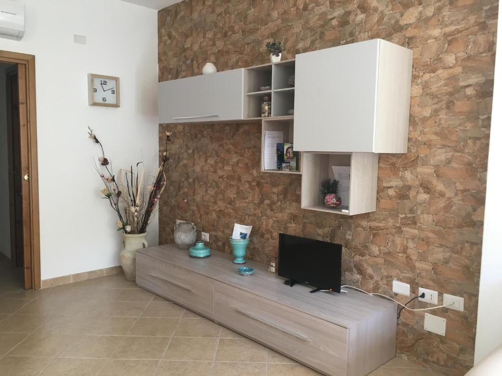 a living room with a tv and a brick wall at Casa Elena in Dorgali