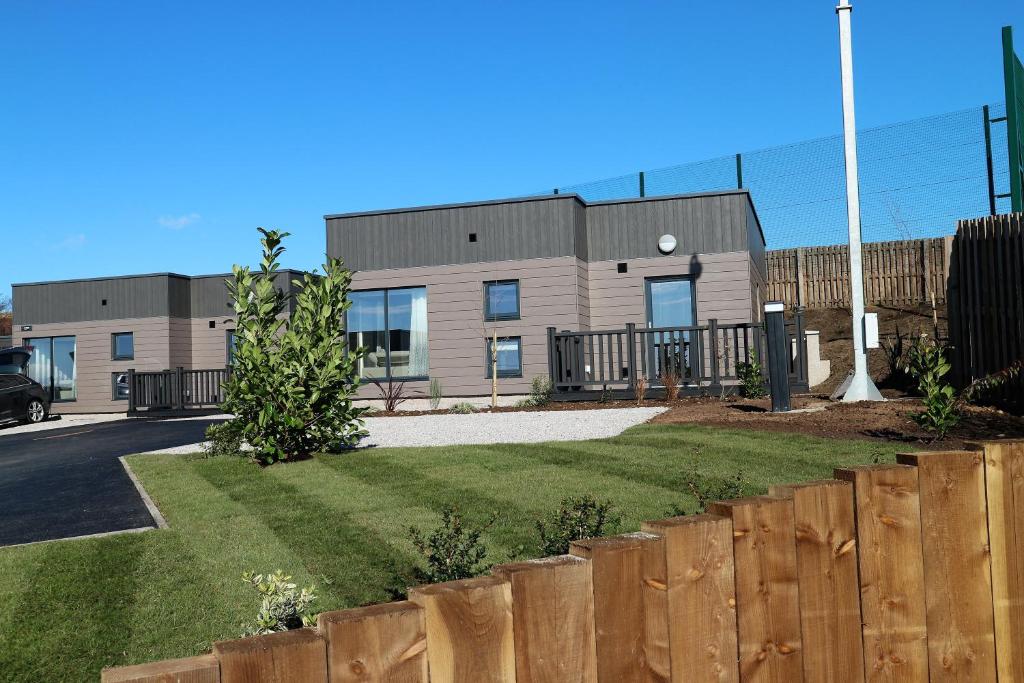 a house with a fence in front of it at Dalriada Lodges Brachans in Stonehaven