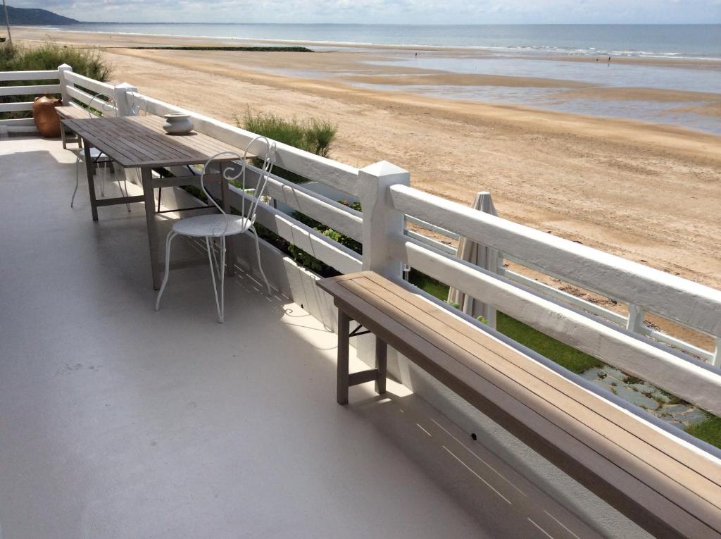 einen Holztisch und Stühle am Strand in der Unterkunft Les pieds dans l'eau in Blonville-sur-Mer