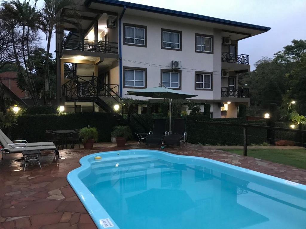 a house with a swimming pool in front of a building at Ocio Apart in Puerto Iguazú