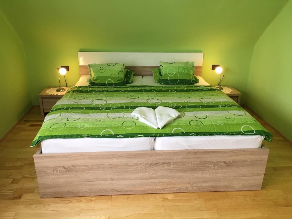ein Schlafzimmer mit einem großen Bett mit einer grünen Bettdecke in der Unterkunft Németh Vendégház in Bük