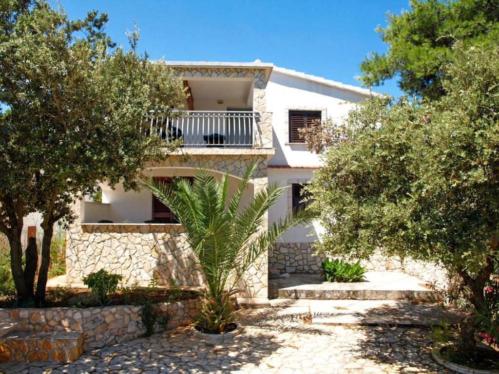 a white house with a balcony and trees at Apartmani Ruk in Vrbanj