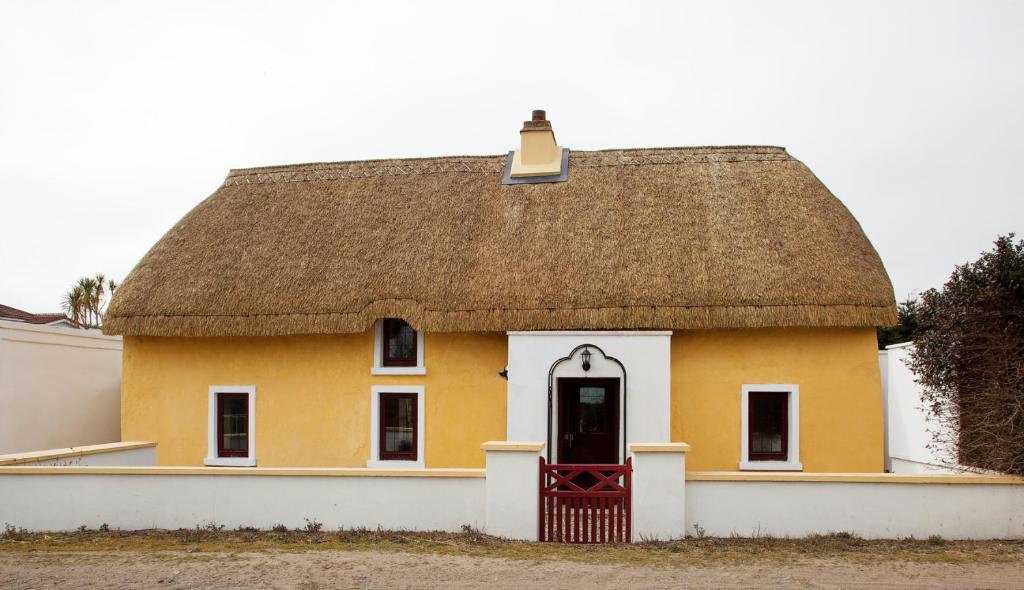 a yellow house with a thatched roof at Sutton Cottage in Wexford