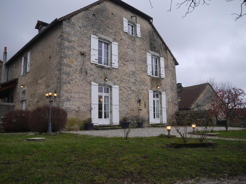 un gran edificio de ladrillo con ventanas blancas y patio en Maison d'Eusébia, en Château-Chalon