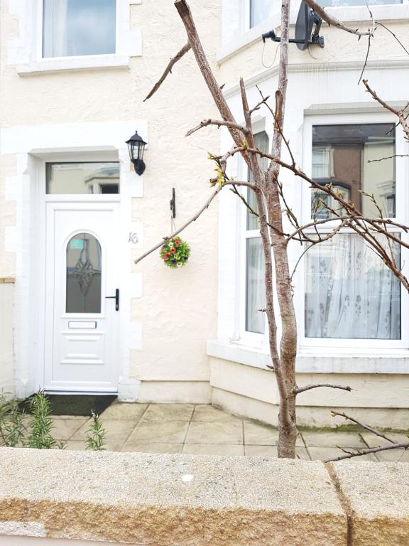 uma porta branca da frente de uma casa branca com um vaso de flores em Llandudno holiday home em Llandudno