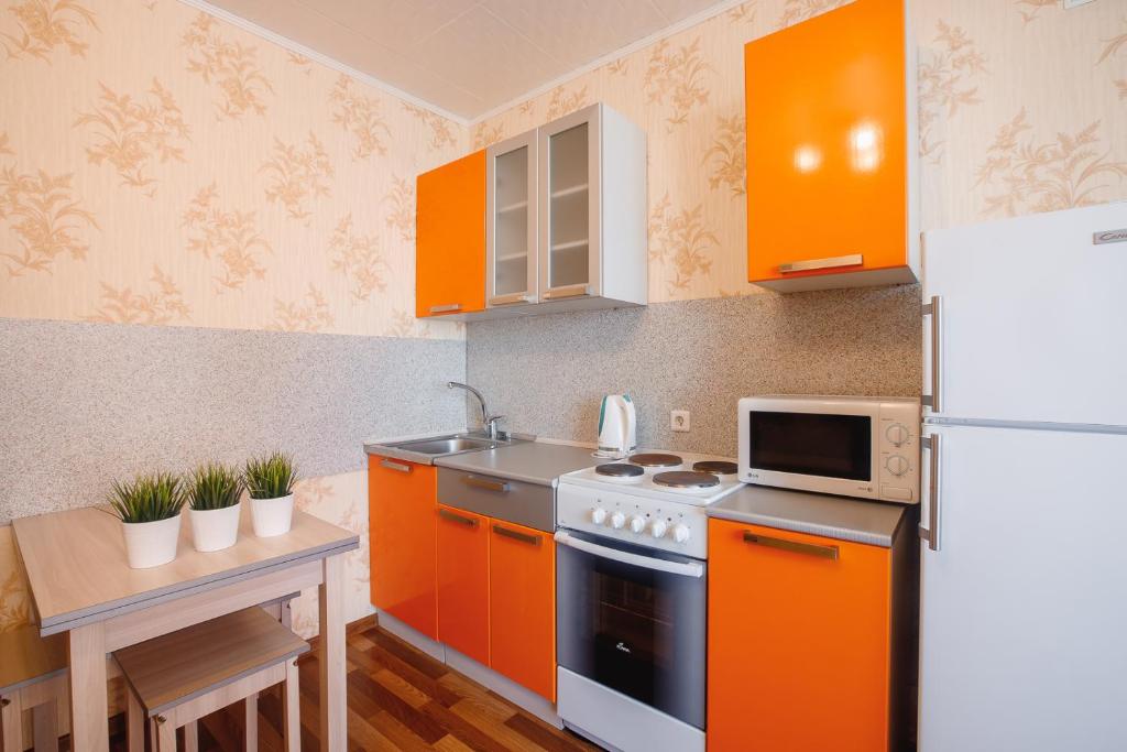 トムスクにあるАпартаменты на Савиныхのキッチン(オレンジ色のキャビネット、白い冷蔵庫付)