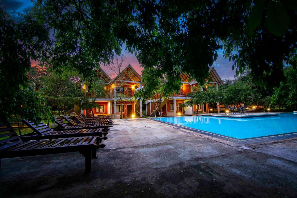 a swimming pool with lounge chairs in front of a house at Elephas Resort & Spa in Sigiriya