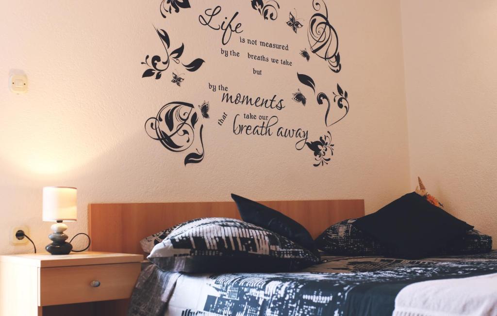 1 dormitorio con 1 cama con palabras en la pared en Apartment & Rooms Marigold, en Baška Voda