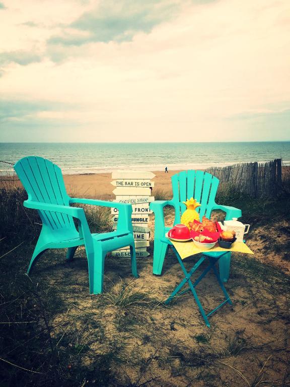 - deux chaises et une table avec de la nourriture sur la plage dans l'établissement LES PIEDS DANS L'EAU, à Merville-Franceville-Plage