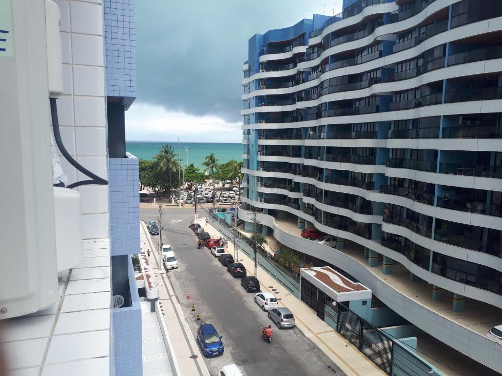 a view of a building and a street with a beach at Maceió Pajuçara Ed. Neo 1 in Maceió