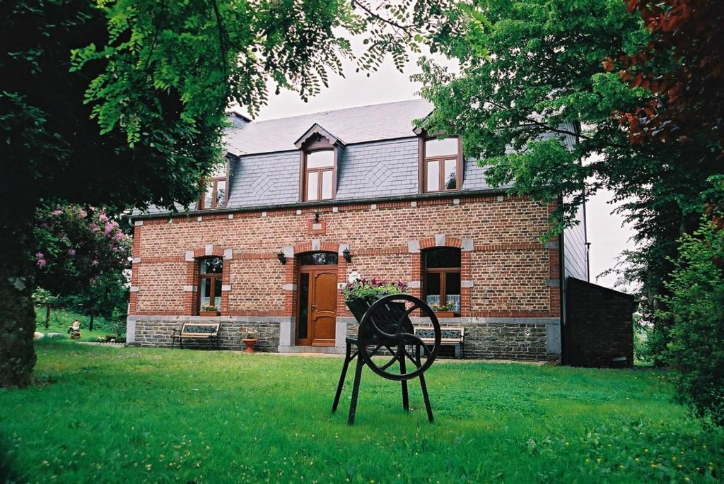une chaise dans l'herbe devant une maison en briques dans l'établissement Chez Basile, à Oizy