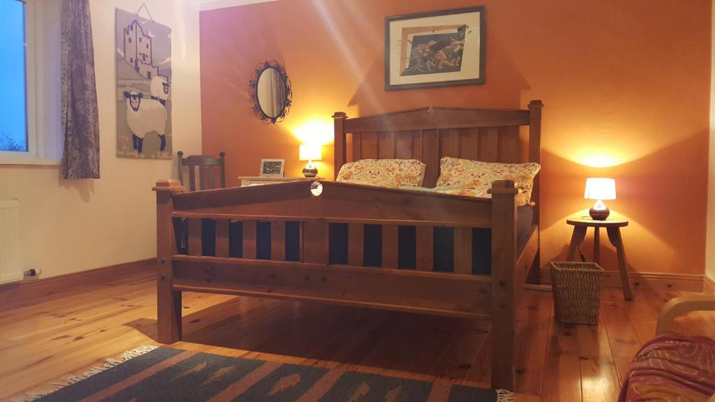 スキバリーンにあるDriftwood Country Roomsのベッドルーム1室(大型木製ベッド1台、ランプ2つ付)