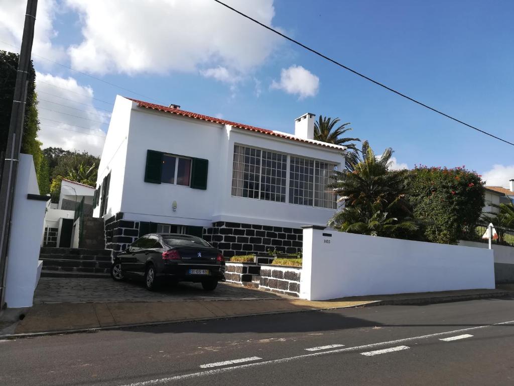 una casa bianca con una macchina parcheggiata di fronte di Family Holiday Villa Vacation Ponta Delgada a Ponta Delgada