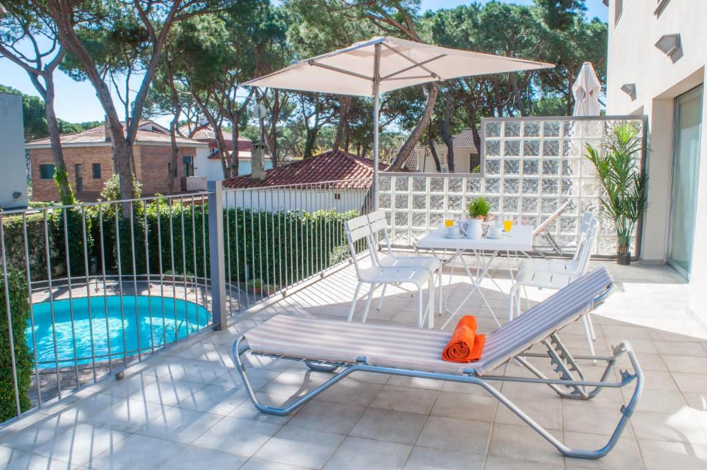 un patio con mesa y sombrilla junto a la piscina en Apartamentos Porta Coeli en Castelldefels