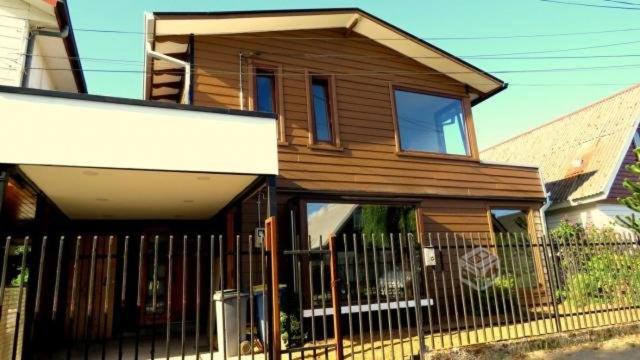 une maison en bois avec une clôture devant elle dans l'établissement Hospedaje Las Animas Valdivia, à Valdivia