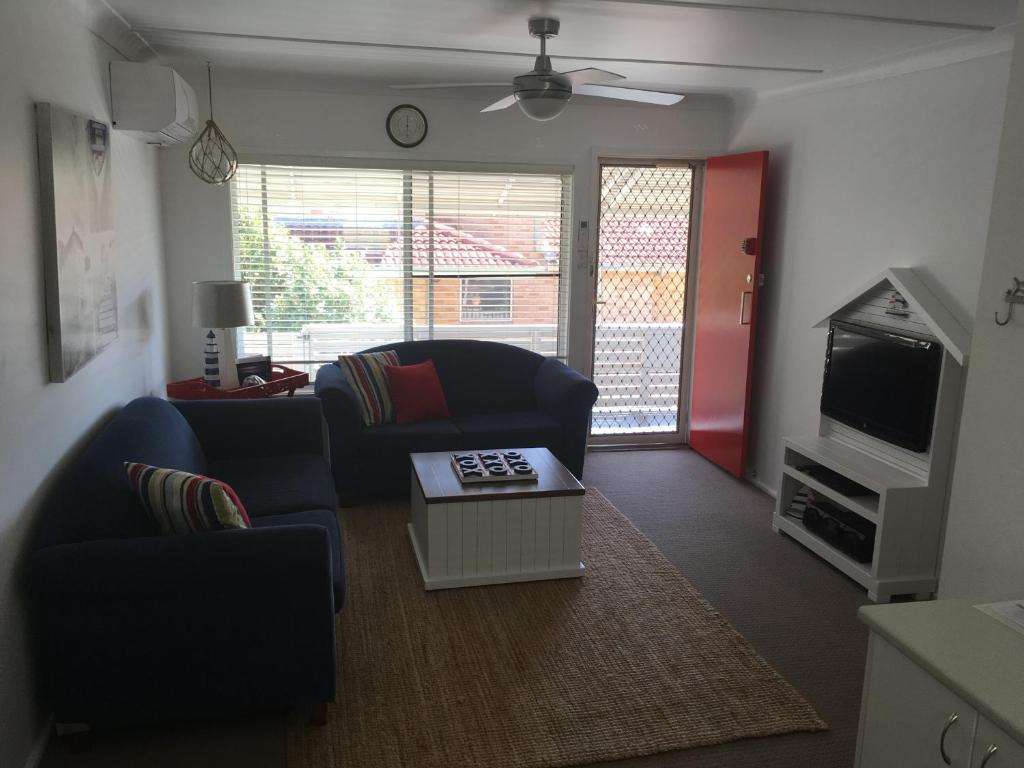 a living room with two couches and a tv at Tomaree Lodge in Nelson Bay