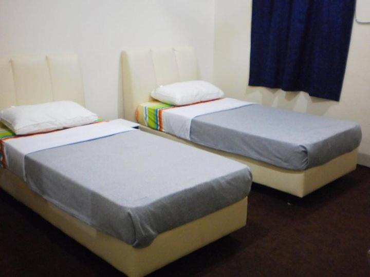 dwa łóżka siedzące obok siebie w pokoju w obiekcie Kerteh Inn w Kerteh
