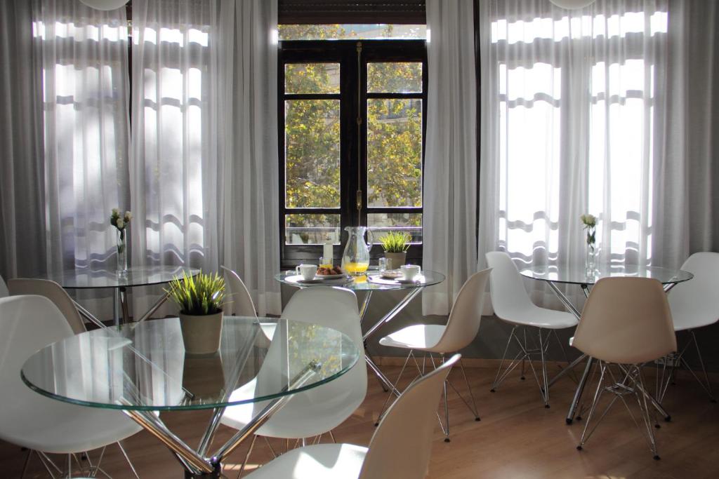 uma sala de jantar com uma mesa de vidro e cadeiras brancas em 7 Moons Bed & Breakfast em Valência