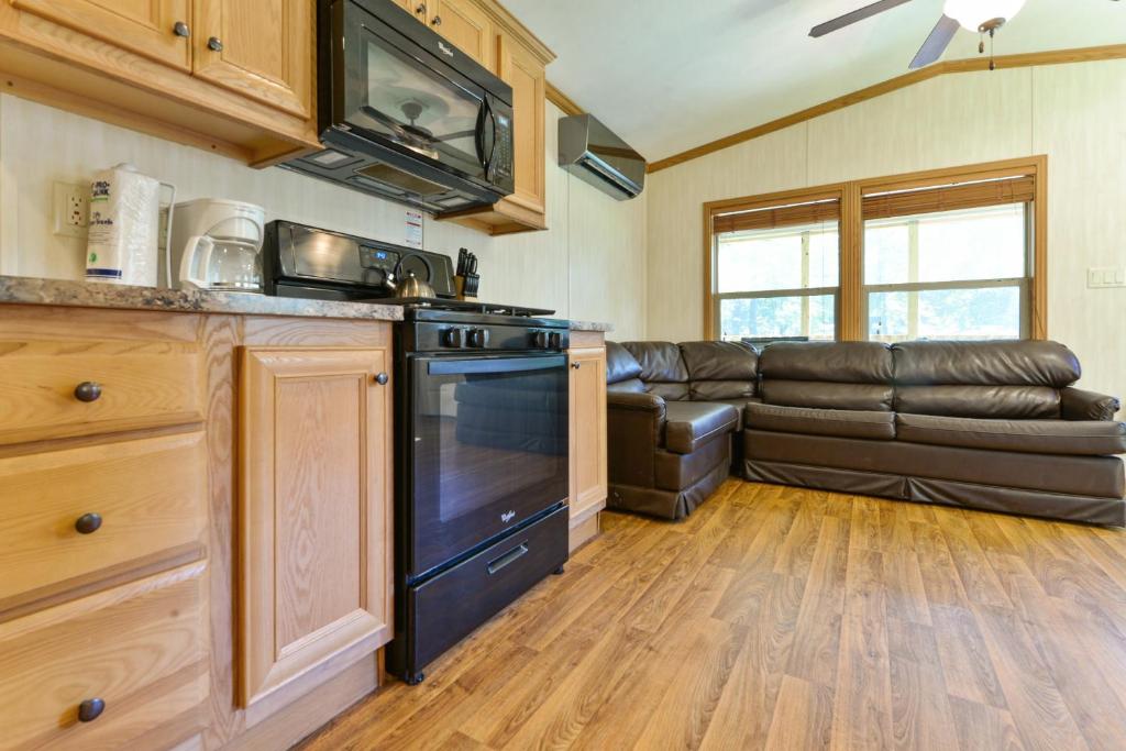 a kitchen and living room with a leather couch at Rondout Valley Camping Resort Deluxe Park Model 11 in Accord