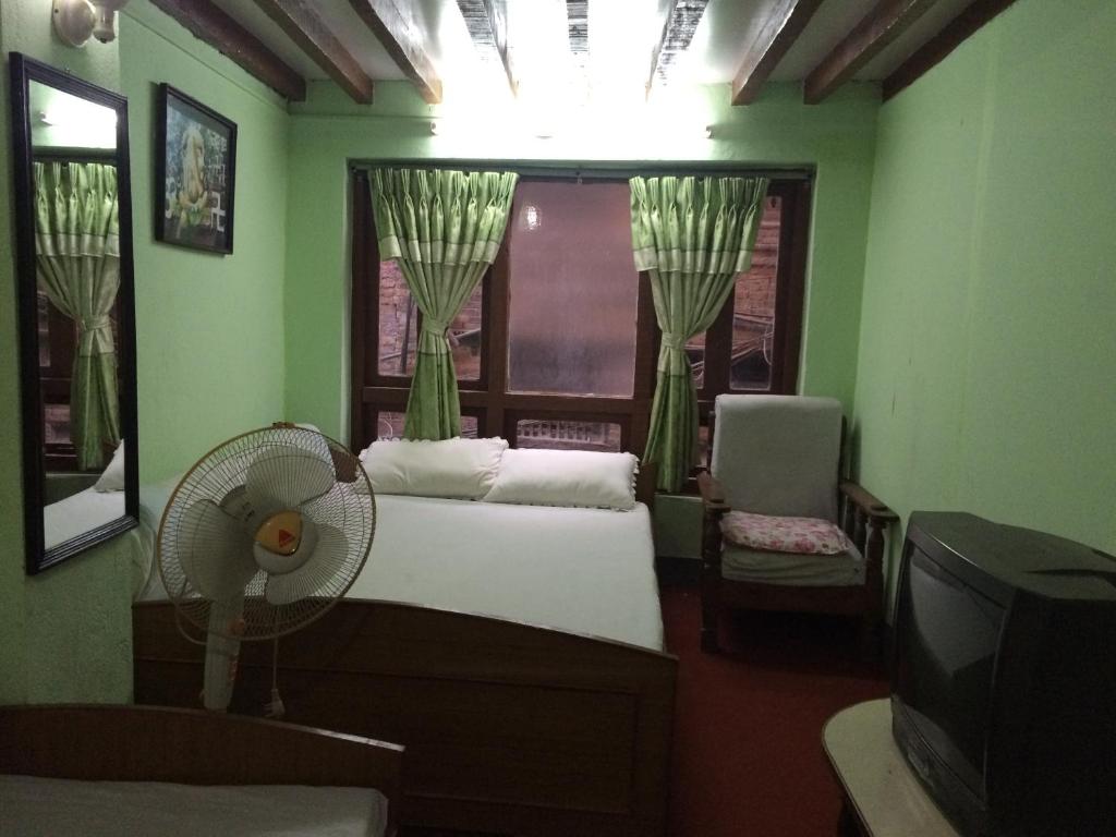 a bedroom with a bed and a window with a fan at Ajima Guest House in Bhaktapur