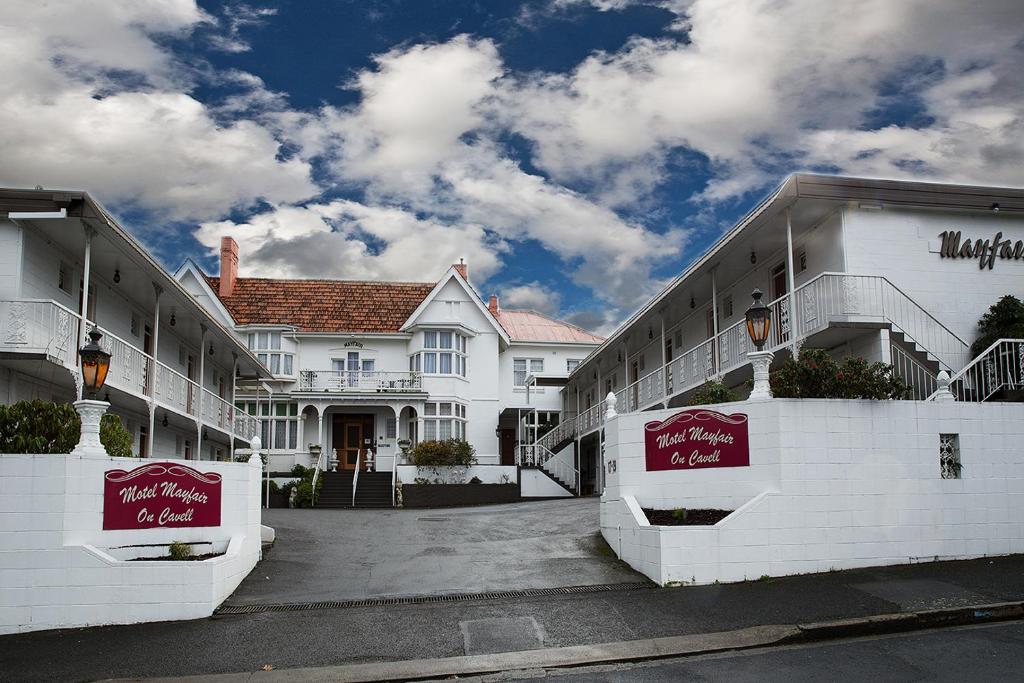 um edifício branco com sinais vermelhos à frente em Motel Mayfair on Cavell em Hobart