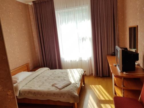 a bedroom with a bed and a television and a window at Гостиница "Алтын Орда" in Astana