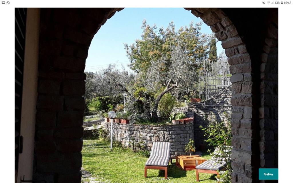 een boog met twee stoelen en een stenen muur bij La collina degli olivi in Carmignano